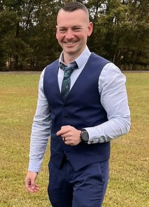 Ian Provencher, standing outdoors in a navy waistcoat and tie